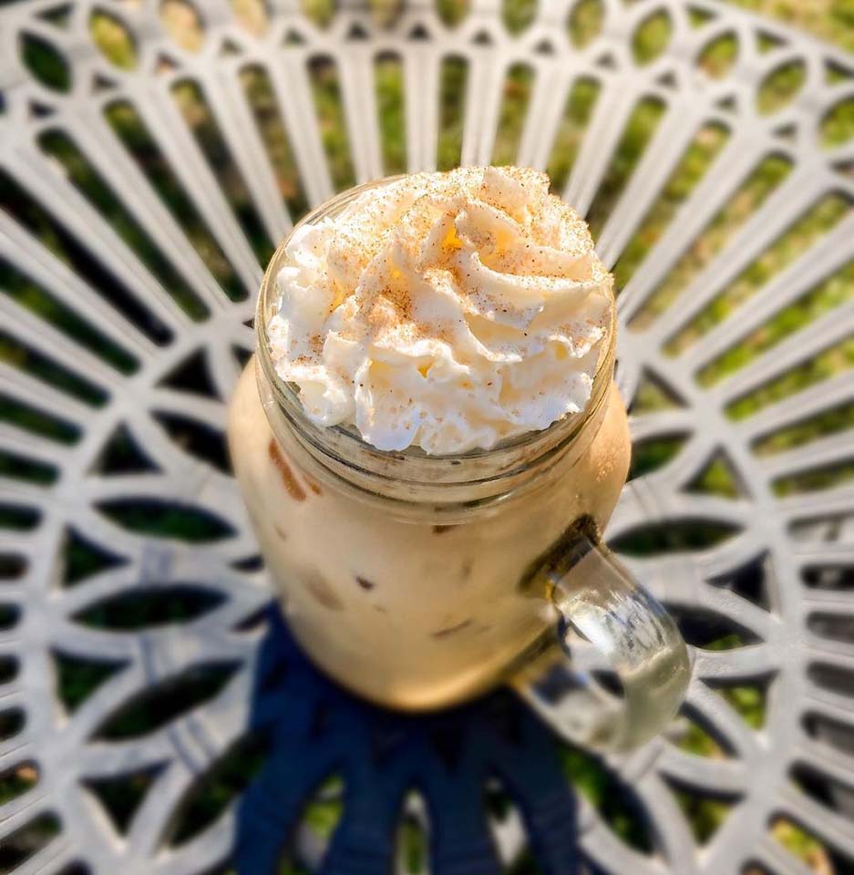 A delicious looking cold coffee with whipped cream, sitting on a table in the sun